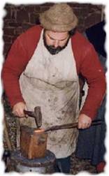 Un artisan qui tape sur une barre de fer avec un marteau...